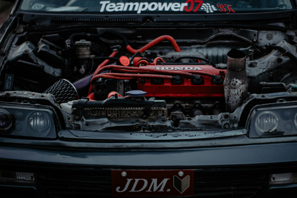 Close-up of a modified Honda engine with red valve cover and custom intake setup