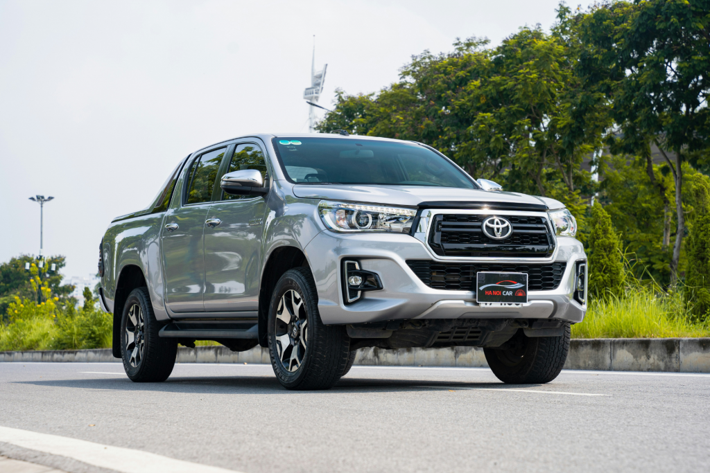 Silver Toyota pickup truck parked on a paved road with green trees in the background
