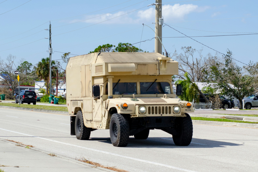 Military Humvee driving on a paved road in a residential area