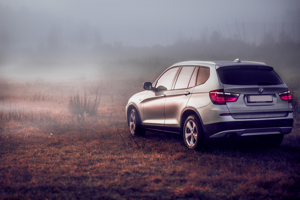 A silver SUV sits alone in a foggy, eerie field at dawn, evoking mystery and the feel of a forgotten journey.