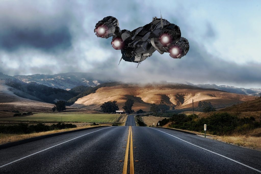 spacecraft hovering over a two-lane rural highway