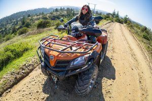 A confident rider pauses on a scenic dirt trail with her rugged orange quad—capturing the freedom and versatility that comes with owning a street legal ATV. - Dirt Legal A confident rider pauses on a scenic dirt trail with her rugged orange quad—capturing the freedom and versatility that comes with owning a street legal ATV.