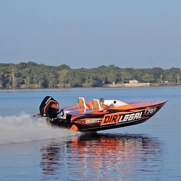 This image shows the Dirt Legal-sponsored Velocity Factory race boat in action, highlighting offshore powerboat racing performance and brand presence.