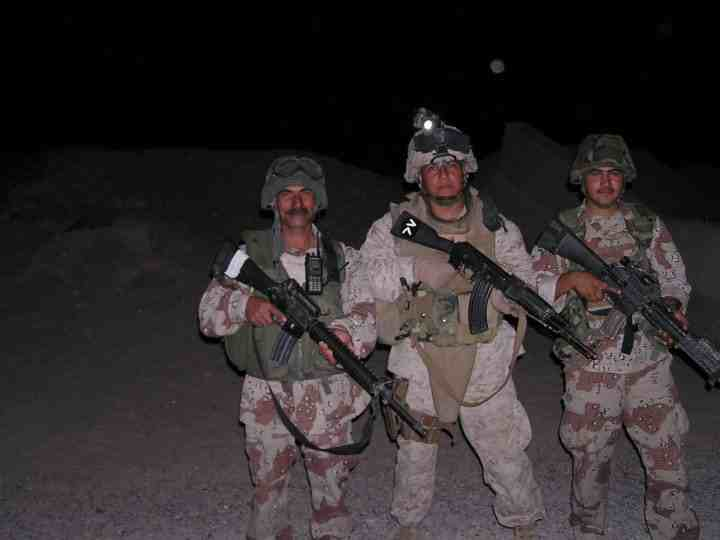Three U.S. soldiers in full combat gear - Dirt Legal Three U.S. soldiers in full combat gear stand together at night in a desert environment, armed and ready, with serious expressions under a dark sky