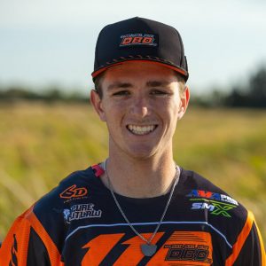 Headshot of Dirt Legal DBDRacing WMR KTM team rider Gage Linville smiling in his orange and black gear and team cap.