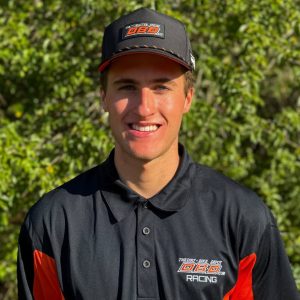 Headshot of Dirt Legal DBDRacing WMR KTM team rider Jaxen Driskell smiling in a black and orange team polo and cap.