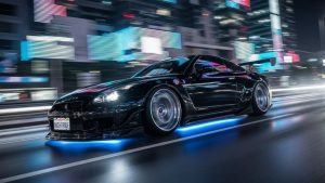 A black modified Nissan GT-R driving through a neon-lit city at night featuring blue LED underglow, a large rear wing, and custom widebody kit.