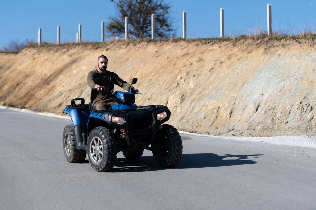 Man riding a blue UTV on a paved road, illustrating how a side-by-side can become street legal with the right equipment and registration.