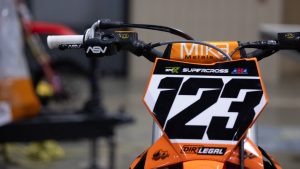 A detailed view of the handlebars and front number plate of Anthony Rodriguez’s KTM dirt bike, featuring ASV levers, Mika Metals bars, and a prominent Dirt Legal logo.