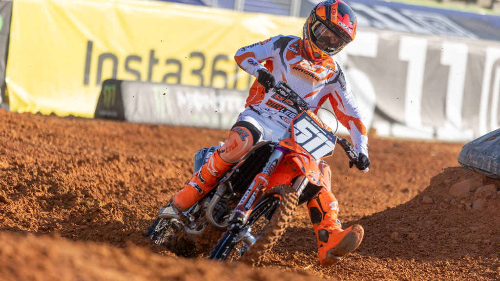 Jace Kessler leaning his Dirt Legal DBDRacing KTM deep into a rutted turn on the Birmingham dirt track during a qualifying session.