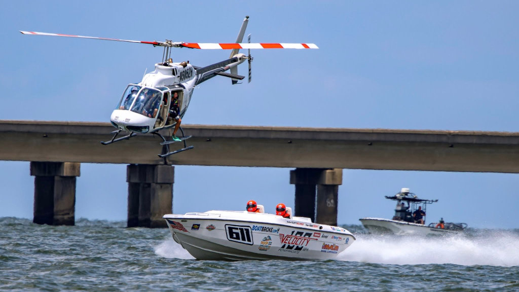 The #611 Ride Legal Velocity powerboat racing on Lake Pontchartrain with a tracking helicopter flying closely overhead.