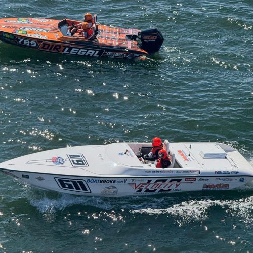 The #611 white Velocity boat and the #789 orange Dirt Legal boat cruising side-by-side on the water during a race weekend.